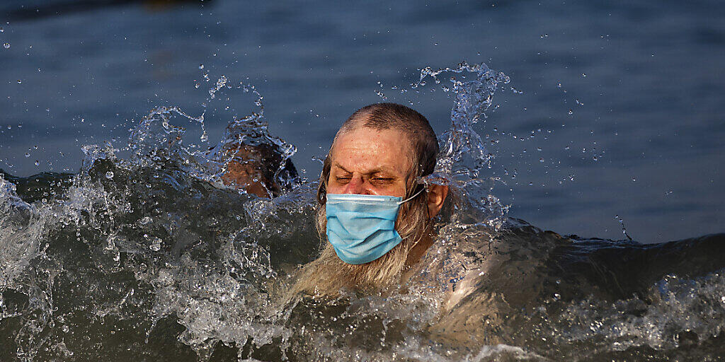 Ein Mann schwimmt mit Mundschutz an einem Strand in Tel Aviv. Foto: Oded Balilty/AP/dpa