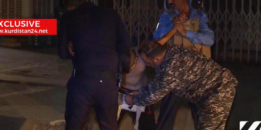 Zwei kurdische Sicherheitskräfte halten einen minderjährigen Selbstmordattentäter fest, während ein dritter den Sprengstoffgärtel entschärft. (Kurdistan 24 TV news) Zwei kurdische Sicherheitskräfte halten einen minderjährigen Selbstmordattentäter fest, während ein dritter den Sprengstoffgärtel entschärft. (Kurdistan 24 TV news)