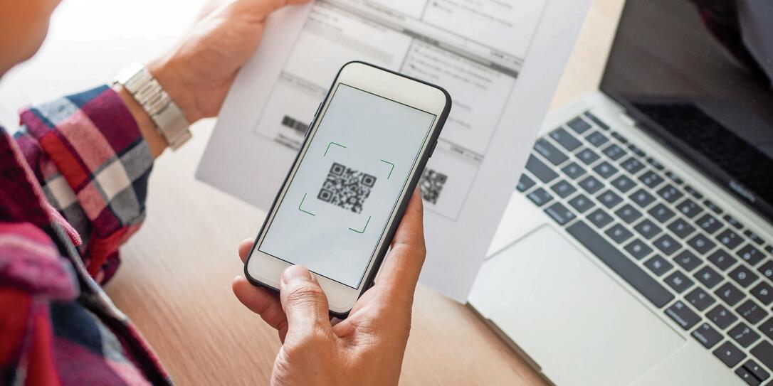 The butler is using a mobile phone to scan the QR code for the bill through the app. Convenient, fast, is an option of modern.