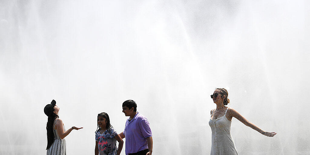 Touristen kühlen sich an einem Sprühregen aus einem Wasserschlauch in Wien.(Themenbild)