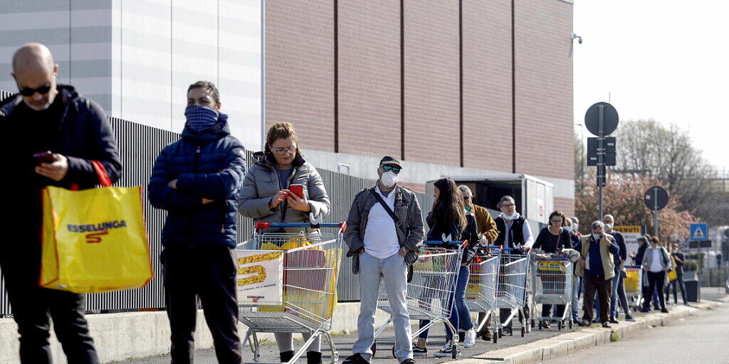 Kundinnen und Kunden warten vor einem Supermarkt in Italien auf Einlass.