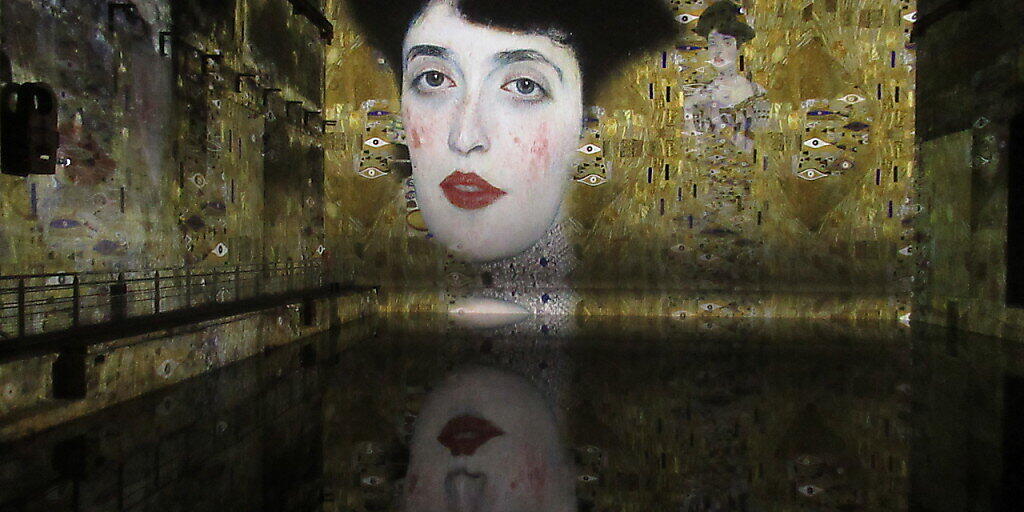 «Die Frau in Gold» von Gustave Klimt spiegelt sich im «Bassins de Lumières». Foto: Sabine Glaubitz/dpa - ACHTUNG: Nur zur redaktionellen Verwendung im Zusammenhang mit einer Berichterstattung über die Ausstellung und nur mit vollständiger Nennung des vorstehenden Credits