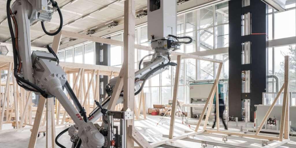 Zwei Roboter arbeiten beim Zusammenbau des Holzmoduls zusammen. Ihr Bewegungspfad wird laufend anhand des Baufortschritts berechnet.