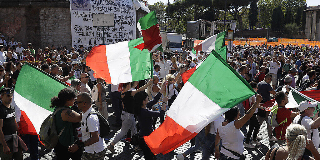 Teilnehmer einer Demonstration gegen die staatliche Corona-Politik schwenken italienische Nationalflaggen. Foto: Gregorio Borgia/AP/dpa Teilnehmer einer Demonstration gegen die staatliche Corona-Politik schwenken italienische Nationalflaggen. Foto: Gregorio Borgia/AP/dpa