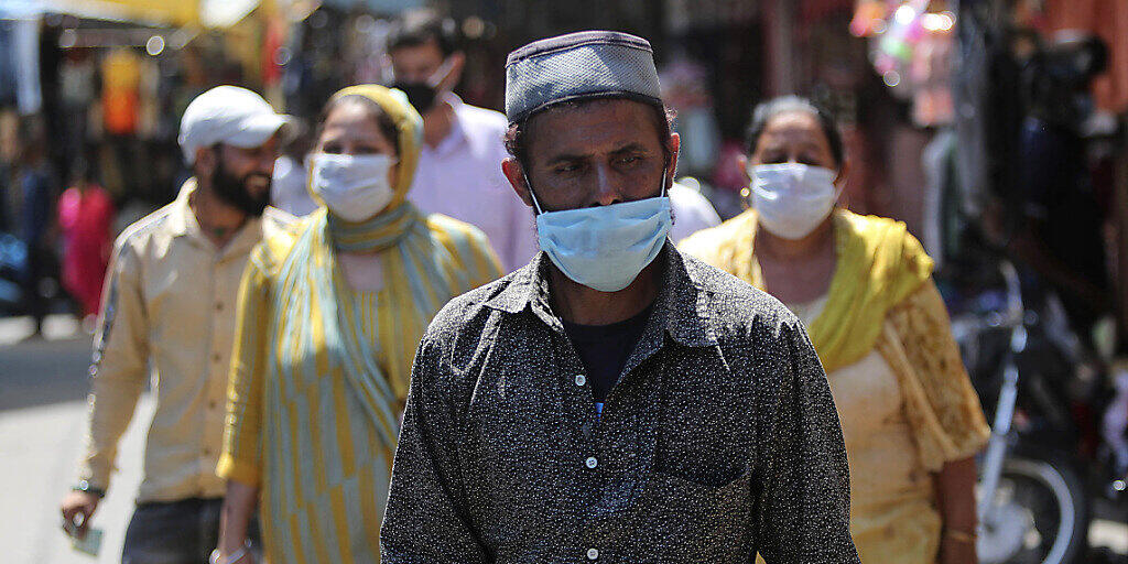 Passanten gehen mit Mundschutz über einen Markt in Jammu. Foto: Channi Anand/AP/dpa