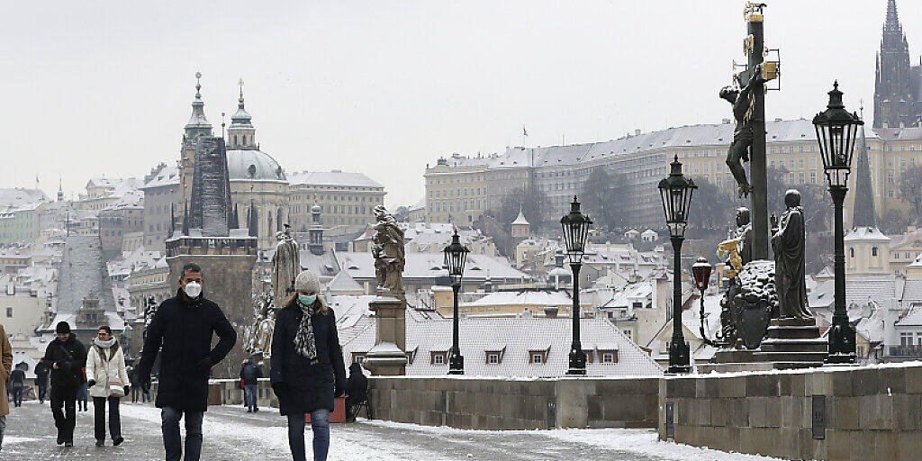Menschen überqueren die mittelalterliche Karlsbrücke nach dem ersten Schneefall in Prag am ersten Tag der Lockerungen der Corona-Maßnahmen in Tschechien nach einem Lockdown. Am Donnerstag durften alle Geschäfte, Einkaufszentren, Restaurants, Bars und Hotels wieder öffnen. Foto: Petr David Josek/AP/dpa Menschen überqueren die mittelalterliche Karlsbrücke nach dem ersten Schneefall in Prag am ersten Tag der Lockerungen der Corona-Maßnahmen in Tschechien nach einem Lockdown. Am Donnerstag durften alle Geschäfte, Einkaufszentren, Restaurants, Bars und Hotels wieder öffnen. Foto: Petr David Josek/AP/dpa