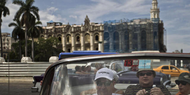 Touristen sitzen in einem amerikanischen Oldtimer in Havanna, Kuba