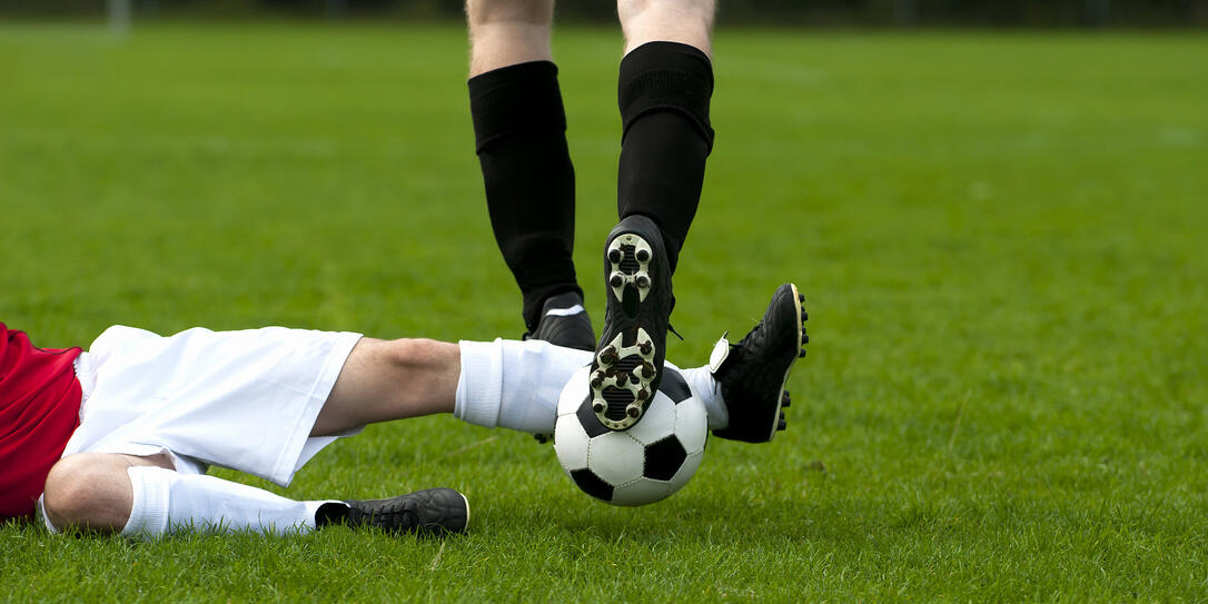 Football player makes tackling to get the soccer ball