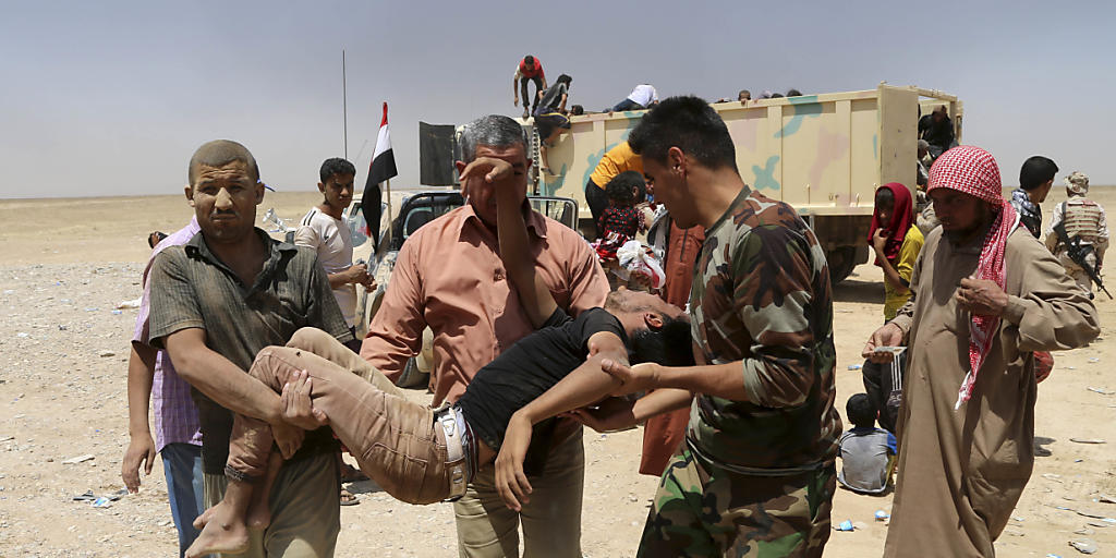 Irakische Soldaten helfen einem erschöpften Flüchtling aus der Umgebung der umkämpften Stadt Mossul. Die internationale Militärkoalition gegen den IS hat verstärkte Anstrengungen im Kampf um Mossul und die syrische Stadt Rakka beschlossen.