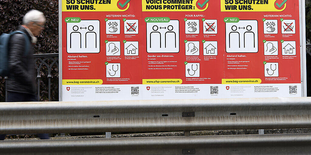 58 neue Infektionen mit dem Coronavirus meldet das BAG am Samstag: Ein Passant vor einer Tafel mit den Hygieieneregeln.