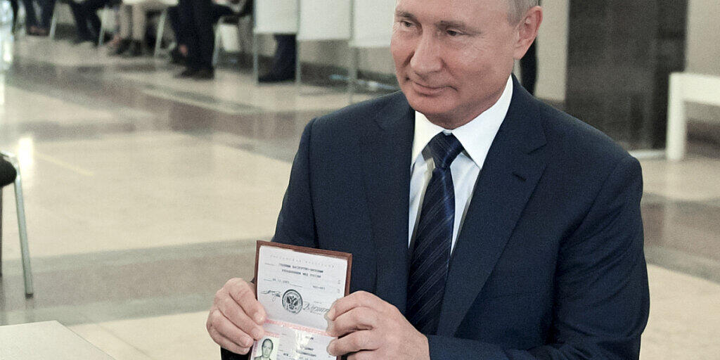 Wladimir Putin, Präsident von Russland, zeigt einer Mitarbeiterin der Wahlkommission seinen Pass in einem Wahllokal. Foto: Alexei Druzhinin/Pool Sputnik Kremlin/AP/dpa