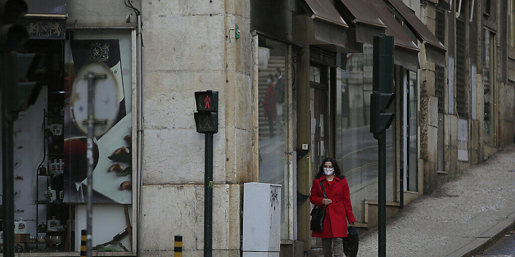 ARCHIV - Eine Frau mit Maske geht eine sehr ruhige Straße in der Innenstadt entlang. Foto: Armando Franca/AP/dpa ARCHIV - Eine Frau mit Maske geht eine sehr ruhige Straße in der Innenstadt entlang. Foto: Armando Franca/AP/dpa