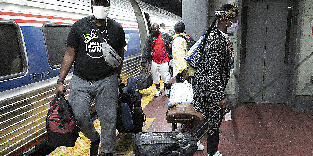 Reisende mit Mundschutz an einem Bahnhof in New York. Foto: Mark Lennihan/AP/dpa