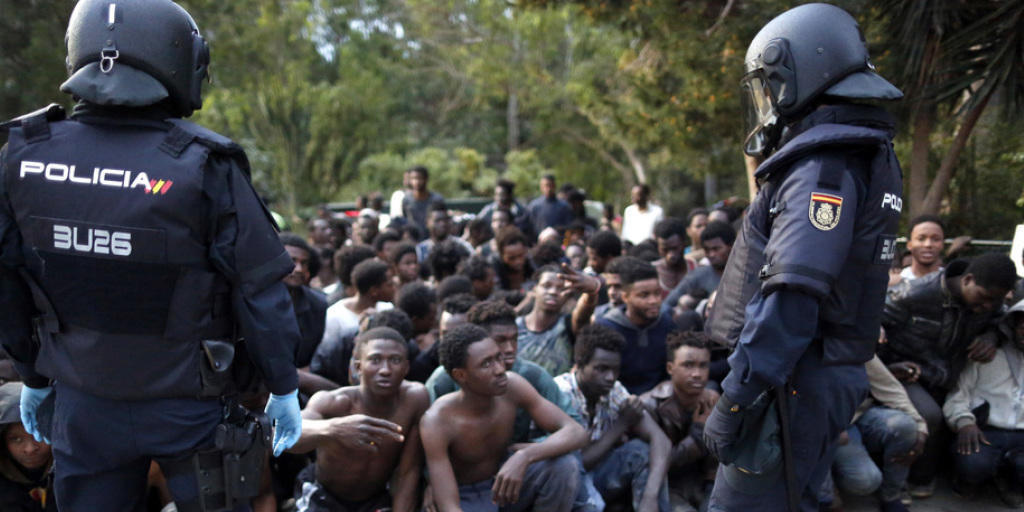 Von der Polizei bewachte Flüchtlinge nach der Überwindung des Grenzzauns am Freitag in Ceuta. Von der Polizei bewachte Flüchtlinge nach der Überwindung des Grenzzauns am Freitag in Ceuta.