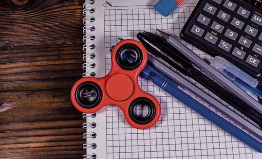 Spinner and different stationeries on wooden desk. Top view