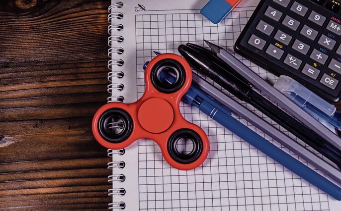 Spinner and different stationeries on wooden desk. Top view