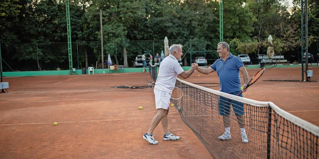 Two senior friends handshake before they start to play tennis