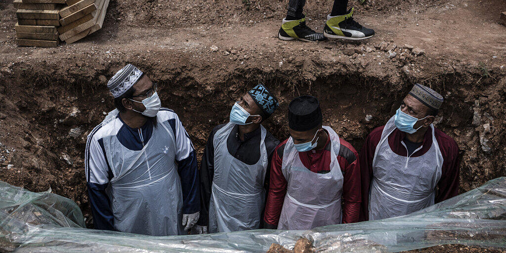 dpatopbilder - Bestatter in Schutzkleidung bereiten das Grab für eine an dem Coronavirus verstorbenen Person auf dem Avalon-Friedhof in Johannesburg für die Beerdigung vor. Foto: Shiraaz Mohamed/AP/dpa