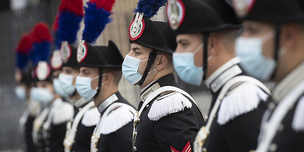 Eine Gruppe italienischer Carabinieri trägt während der Feierlichkeiten zum Tag der Streitkräfte Mund-Nasen-Schutz. Foto: Alessandra Tarantino/AP/dpa