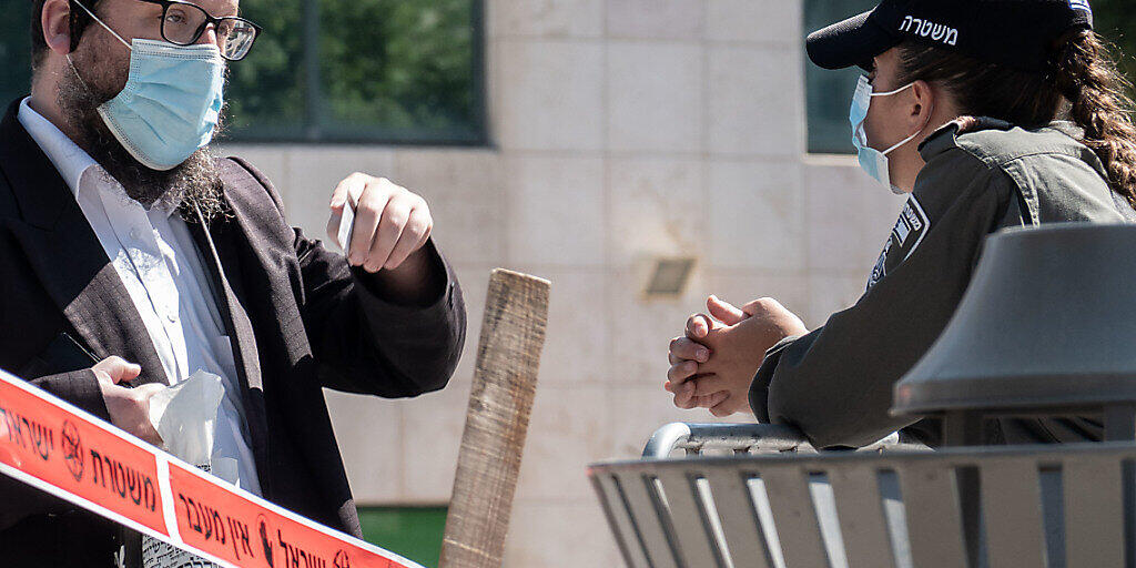Eine Polizistin prüft den Ausweis eines jüdischen Anwohners in Jerusalem. Die israelische Regierung führt erneut Lockdown-Maßnahmen ein. Foto: Nir Alon/ZUMA Wire/dpa