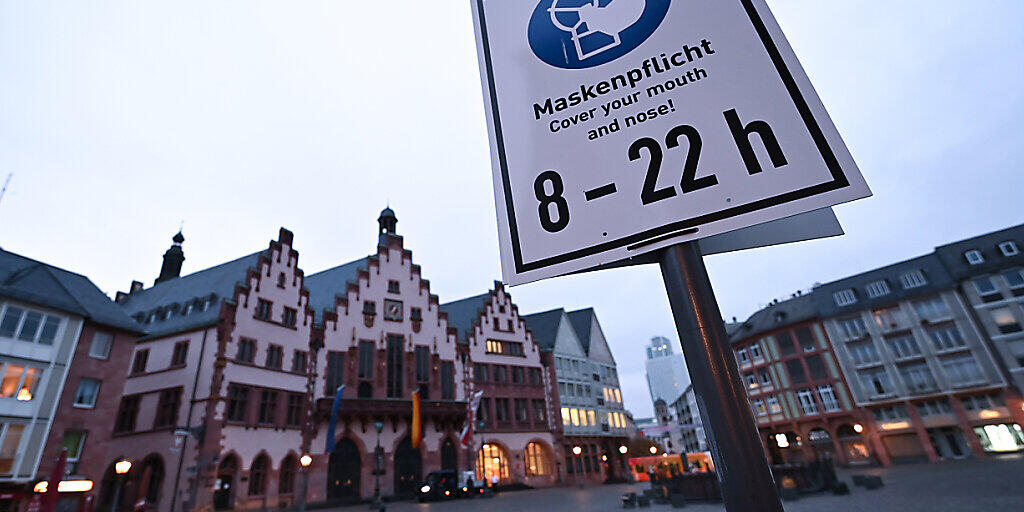 Ein Schild mit der Aufschrift "Maskenpflicht. Cover your mouth and nose! 8 - 22 h" ist auf dem Römerberg an einem Laternenpfahl befestigt. Nach der Video-Konferenz mit der Kanzlerin hat Hessens Landesregierung hat noch keine Entscheidung über möglicherweise verschärfte Corona-Regeln getroffen. Foto: Arne Dedert/dpa Ein Schild mit der Aufschrift "Maskenpflicht. Cover your mouth and nose! 8 - 22 h" ist auf dem Römerberg an einem Laternenpfahl befestigt. Nach der Video-Konferenz mit der Kanzlerin hat Hessens Landesregierung hat noch keine Entscheidung über möglicherweise verschärfte Corona-Regeln getroffen. Foto: Arne Dedert/dpa