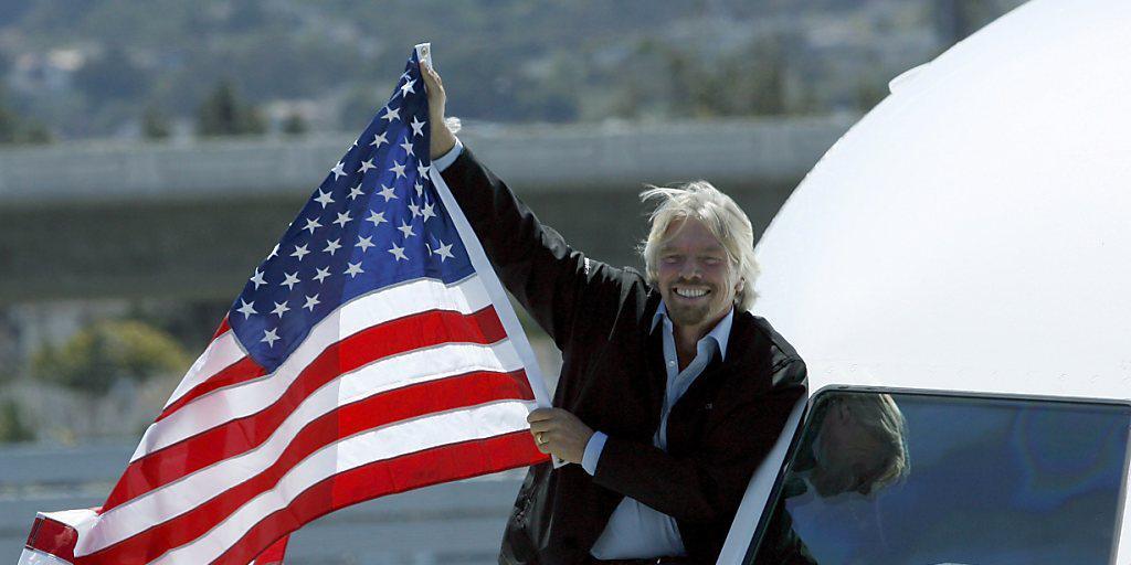Alaska Air kauft seine Fluggesellschaft: Richard Branson hält eine US-Flagge aus dem Fenster eines Virgin-America-Fliegers. Alaska Air kauft seine Fluggesellschaft: Richard Branson hält eine US-Flagge aus dem Fenster eines Virgin-America-Fliegers.