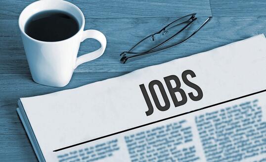 Cup of coffee, reading glasses and a newspaper with job advertisements during a job search