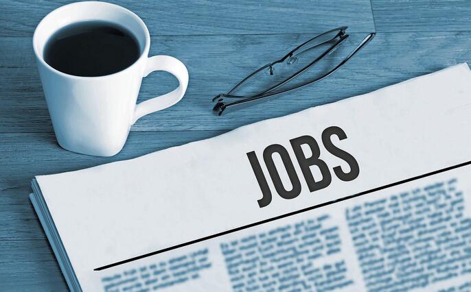 Cup of coffee, reading glasses and a newspaper with job advertisements during a job search