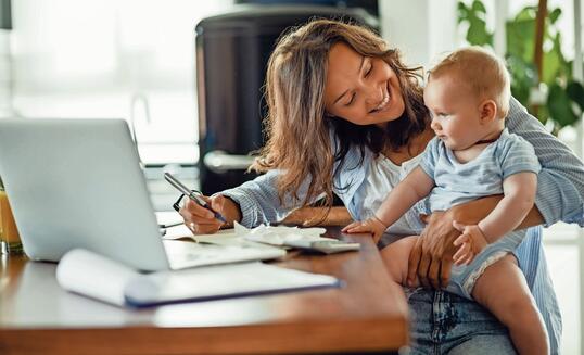 Happy mother talking to her baby while working at home.