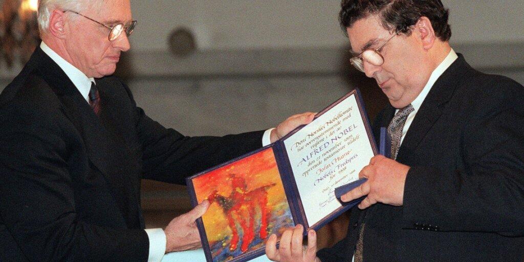 ARCHIV - John Hume (r), ehemaliger Vorsitzender der Social Democratic and Labour Party (SDLP), schaut auf das Friedensnobelpreisdiplom, das er von Francis Sejersted, damals Vorsitzender des norwegischen Friedensnobelpreiskomitees, während der Verleihungszeremonie im Osloer Rathaus erhielt. Foto: Bjoern Sigurdsoen/NTB POOL/AP/dpa