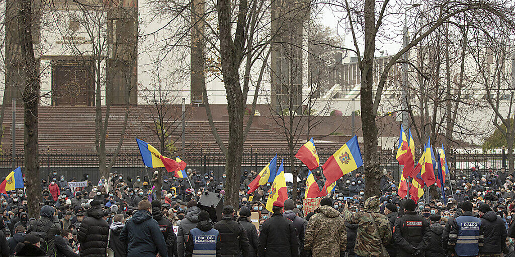 Demonstranten schwenken Fahnen und versammeln sich zu einem Protest zur Unterstützung der gewählten Präsidentin Sandu vor dem Parlamentsgebäude. Tausende Protestierende sind in der Republik Moldau für ihre gewählte Präsidentin Sandu auf die Straße gegangen. Foto: Roveliu Buga/AP/dpa