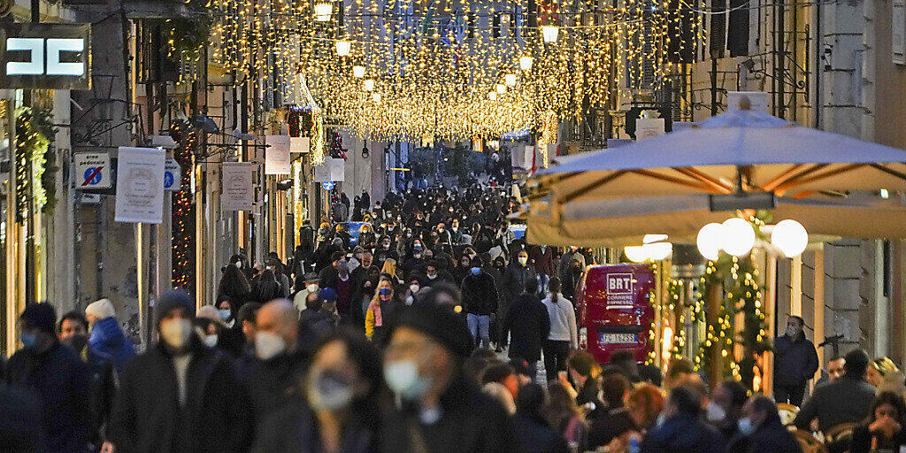 Zahlreiche Menschen mit Mund-Nasen-Schutz gehen eine weihnachtlich geschmückte Einkaufsstraße in der Innenstadt entlang. Foto: Andrew Medichini/AP/dpa Zahlreiche Menschen mit Mund-Nasen-Schutz gehen eine weihnachtlich geschmückte Einkaufsstraße in der Innenstadt entlang. Foto: Andrew Medichini/AP/dpa